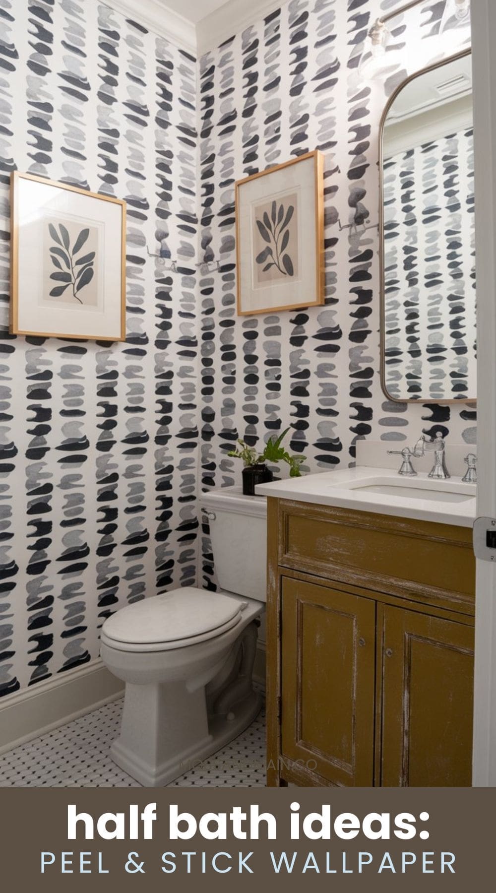 A small bathroom features abstract black and gray patterned peel-and-stick wallpaper. There are framed leaf prints on the wall. A white toilet and a wooden vanity with a marble countertop are also present. Text at the bottom says half bath ideas: peel & stick wallpaper.