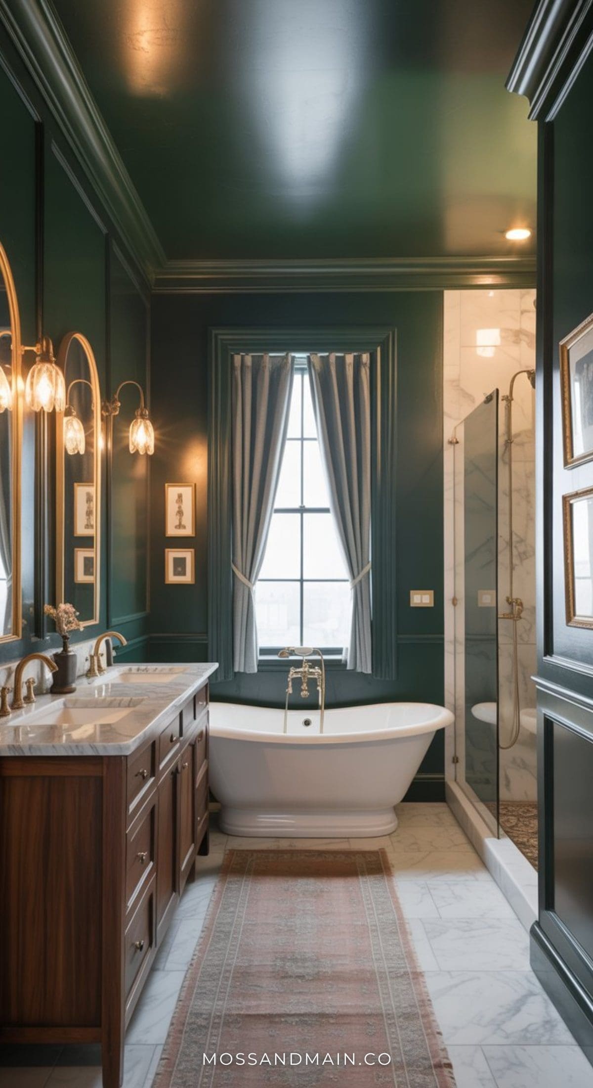 A stylish dark green bathroom features a freestanding white tub under a window with gray curtains, a double vanity with mirrors, and a glass shower with marble accents. Elegant sconces and framed art add warmth to the space.