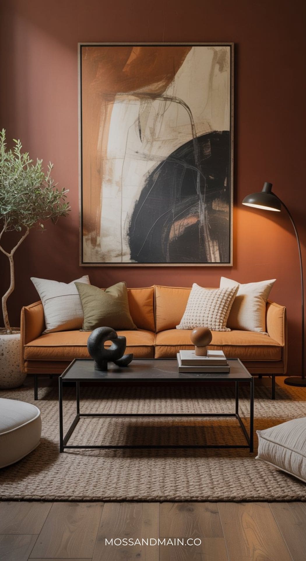 A sophisticated living room with a tan sofa, abstract wall art, black floor lamp, coffee table with decorative items, potted plant, and textured rug on wood flooring—perfect for those seeking cozy and stylish living room ideas in warm, earthy tones.